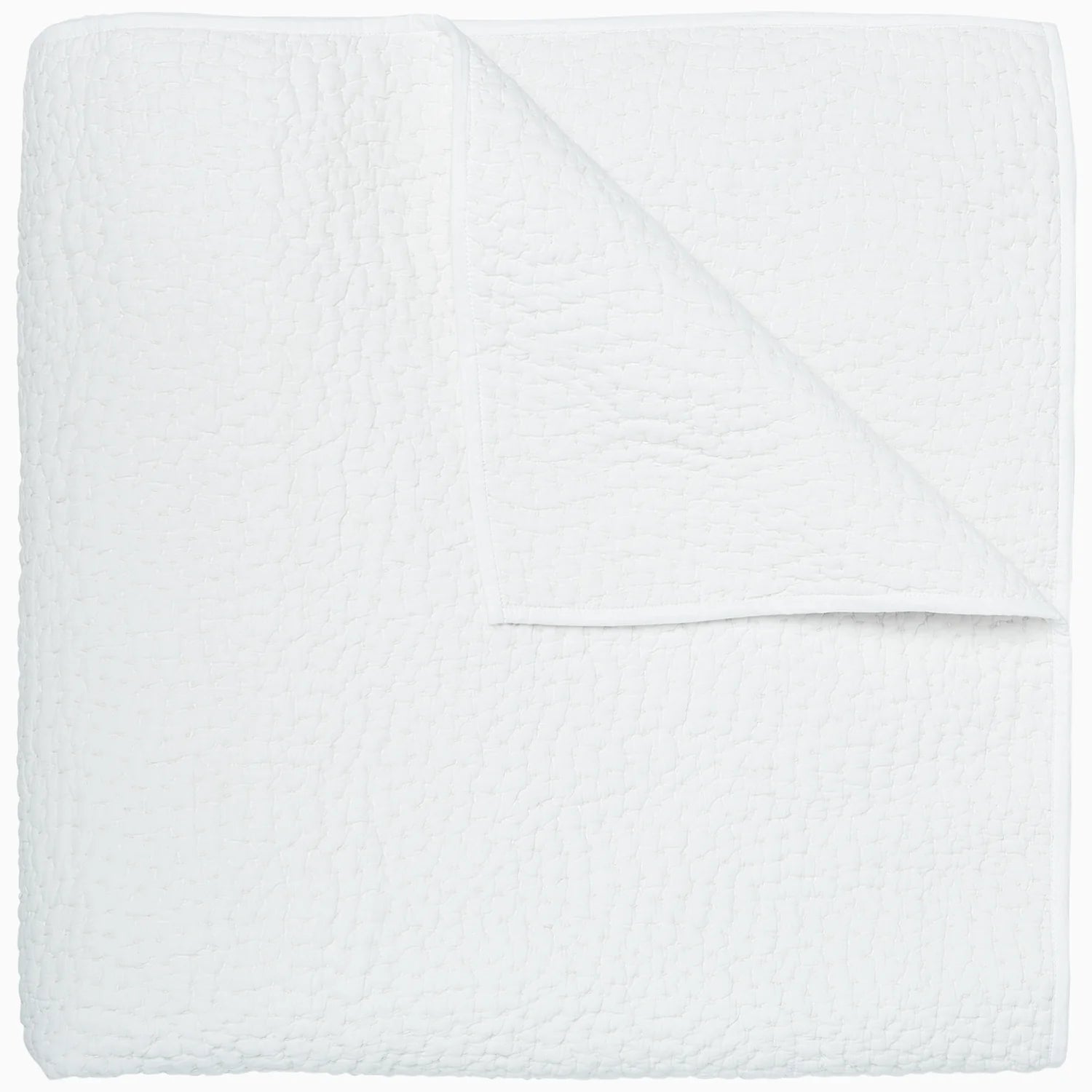A plain white textured blanket neatly folded over in a Scottsdale Arizona bungalow, displaying a smooth and soft quilted pattern.