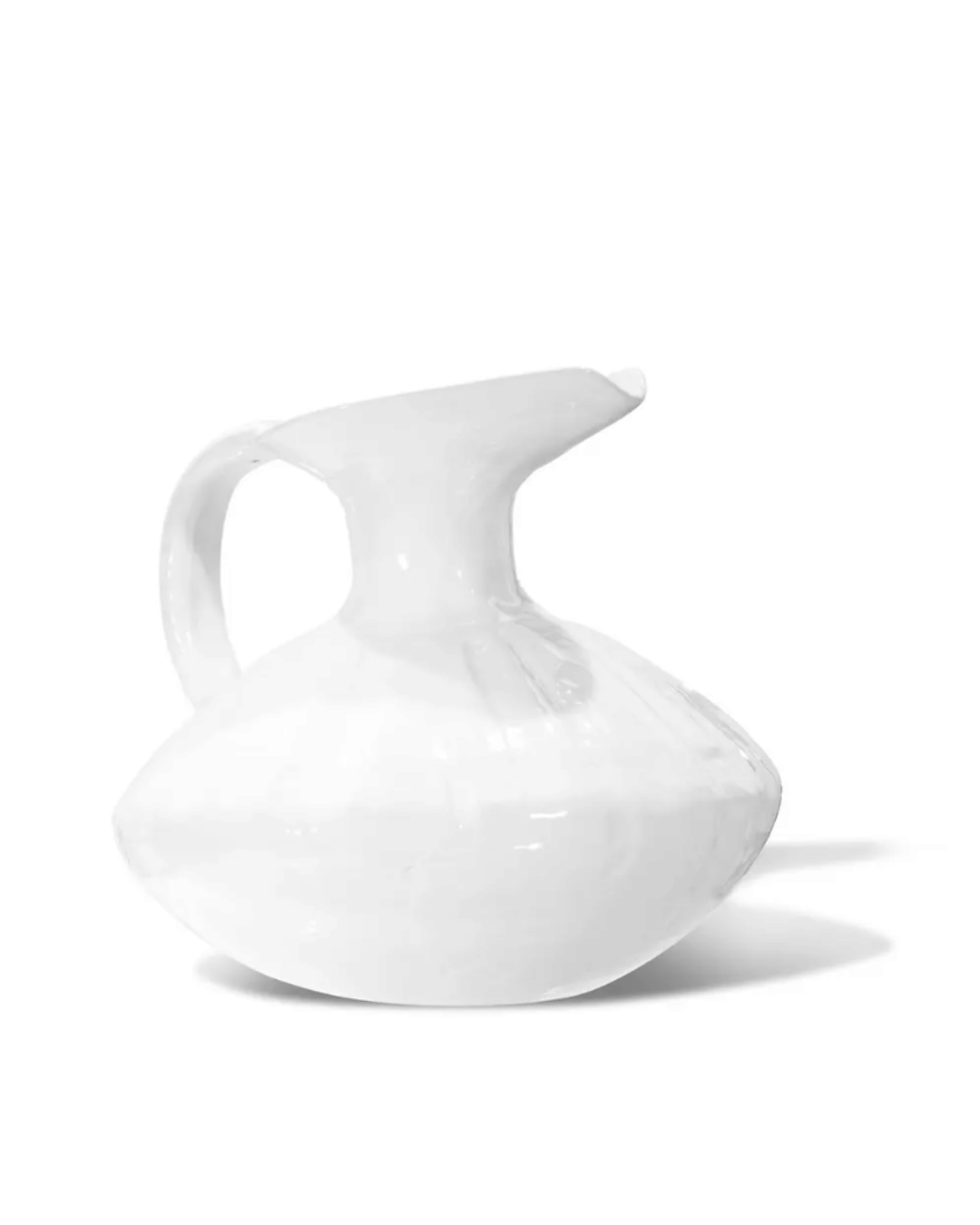 A white ceramic Pitcher No. 431 from Montes Doggett with a glossy finish, uniquely shaped with an asymmetrical, swollen body and a wide, angular handle, displayed against a clean, white background in a Scottsdale Arizona bungalow.
