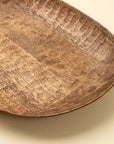 Hand-carved mango wood dish by Faire Terrain in natural finish, shown on a light beige background.