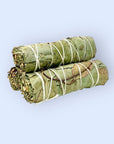 Two Faire Eucalyptus Smudge bundles, tightly wrapped with white string, rest on a light blue background—ideal for eucalyptus cleansing rituals.