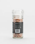 The Faire Pink Himalayan Salt Grinder features coarse Himalayan salt crystals in a refillable glass grinder with a clear plastic top and a black label, displayed simply against a plain white background.