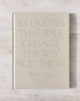 A beige hardcover copy of "101 Quotes That Will Change the Way You Think" by Faire rests on a light wooden surface.
