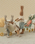 Maileg Micro Pram with carrots and playful bunnies on an indoor rug, styled for a cozy nursery or playroom.