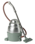 Maileg Furniture by Maileg: a vintage-inspired canister vacuum cleaner with silver top, green base, metal hose, and fabric-wrapped cord—ideal for dollhouse displays or Maileg Mouse scenes—stands upright on a neutral background.