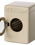 The Maileg Furniture front-loading washing machine by Maileg features a round open door and perforated metal drum. Its beige, rectangular design with simple buttons makes it an adorable dollhouse furniture addition.