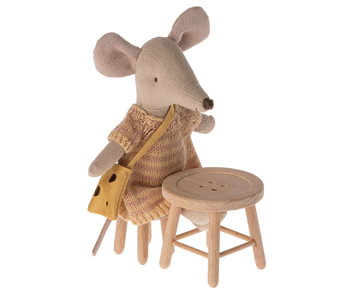 A Maileg Mouse plush doll with a knitted dress and yellow bag sits on Maileg Furniture next to a matching stool, both by Maileg, against a plain background.