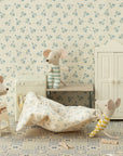 Three toy mice in striped outfits play in a vintage-style laundry room with floral wallpaper, tiled floor, scattered laundry, and Maileg accessories like the Maileg High Chair, washing machine, bench, and wardrobe.