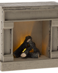 The Maileg Fireplace by Maileg is a small, vintage-finished wooden piece with faux logs and a warm glow, perfect for cozy mouse homes or rustic décor and styled to resemble a classic hearth.