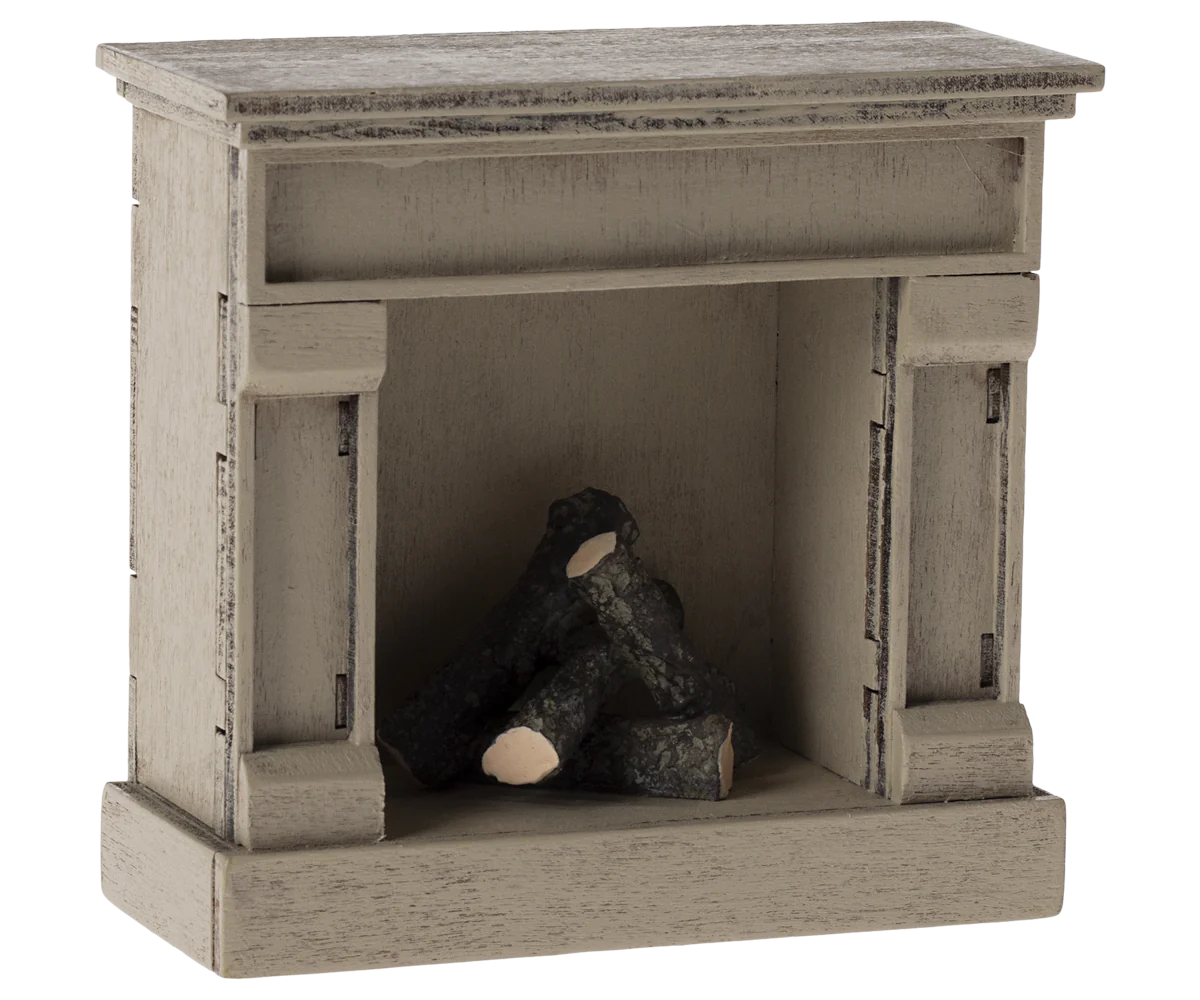 The Maileg Furniture by Maileg is a small wooden decorative fireplace with a rustic finish and three faux logs inside, perfect as dollhouse furniture.