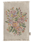 The Maileg Rug by Maileg is a rectangular woven mat with fringed edges and a vibrant floral pattern in pink, yellow, orange, and green on beige. It’s perfect as a doormat or for dollhouses and includes a small fabric tag on one side.
