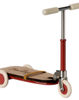 The Maileg Furniture vintage-style scooter by Maileg features a wooden deck, red frame, cream handlebar grips, and three white wheels—perfect for dollhouses or Maileg Mouse playrooms.