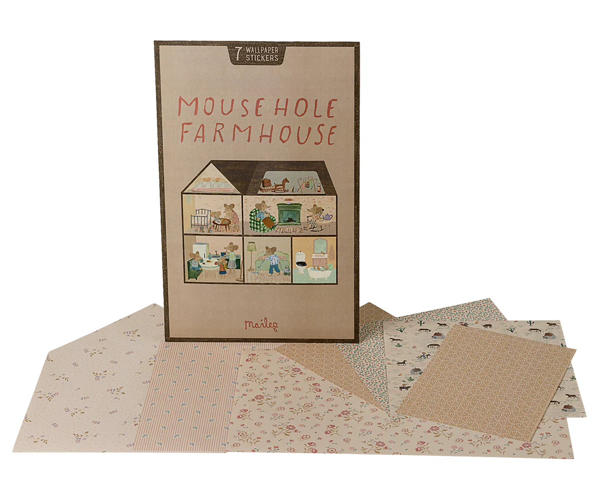 A Maileg Furniture play set box from Maileg stands upright, featuring illustrated rooms on the front. Surrounding it are patterned wallpaper sticker sheets and a variety of colorful Maileg dollhouse furniture pieces.