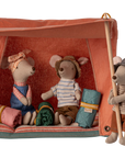 Three Maileg mice prepare for adventure with the Maileg Happy Camper Mouse Tent—two nap in sleeping bags inside the bright orange tent, while another stands outside with a wooden pole, all ready for imaginative play.