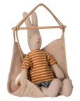 The Maileg Hanging Chair by Maileg features a beige fabric seat hanging from wooden rods, ideal as charming dollhouse furniture or for displaying small stuffed animals.