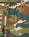Close-up of The Drawn Half-Pipe Ankle by Mother, featuring 100% cotton camouflage fabric with green drawstrings. Shows high-waisted waistband, stitching detail, and shades of green, brown, and beige.