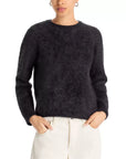 A person wearing the Jumper 1 2 3 4/CR2 Brushed Crew—a fuzzy black cashmere crew neck jumper with long sleeves—and off-white pants, stands with hands in pockets against a plain white background.