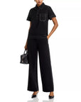 A person is wearing Rag & Bone Irina Pont Contrast Stitch Pants, a black short-sleeve collared shirt with white stitching, black pointed-toe heels, and holding a small black handbag; only part of the face is visible.