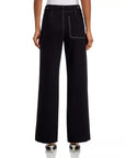A person is seen from the back wearing Rag & Bone's Irina Pont Contrast Stitch Pants—a high-waisted, wide-leg style with relaxed fit, white contrast stitching, a large back pocket, zip fly closure—paired with black heels.