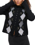 A woman wears the Alex Mill Taylor Cardigan Argyle, a black wool sweater with gray, white, and beige argyle pattern, relaxed fit, paired with a dark skirt. Her face is partially out of frame.
