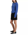 A woman in a textured blue relaxed-fit long-sleeve sweater, black loafers, and the Alex Mill Naomi Mini Skirt stands against a plain white background.