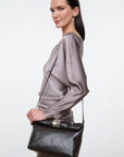 Staud Cuff Clutch in gray silk held by model in gray dress, plain white background, modern minimal style.