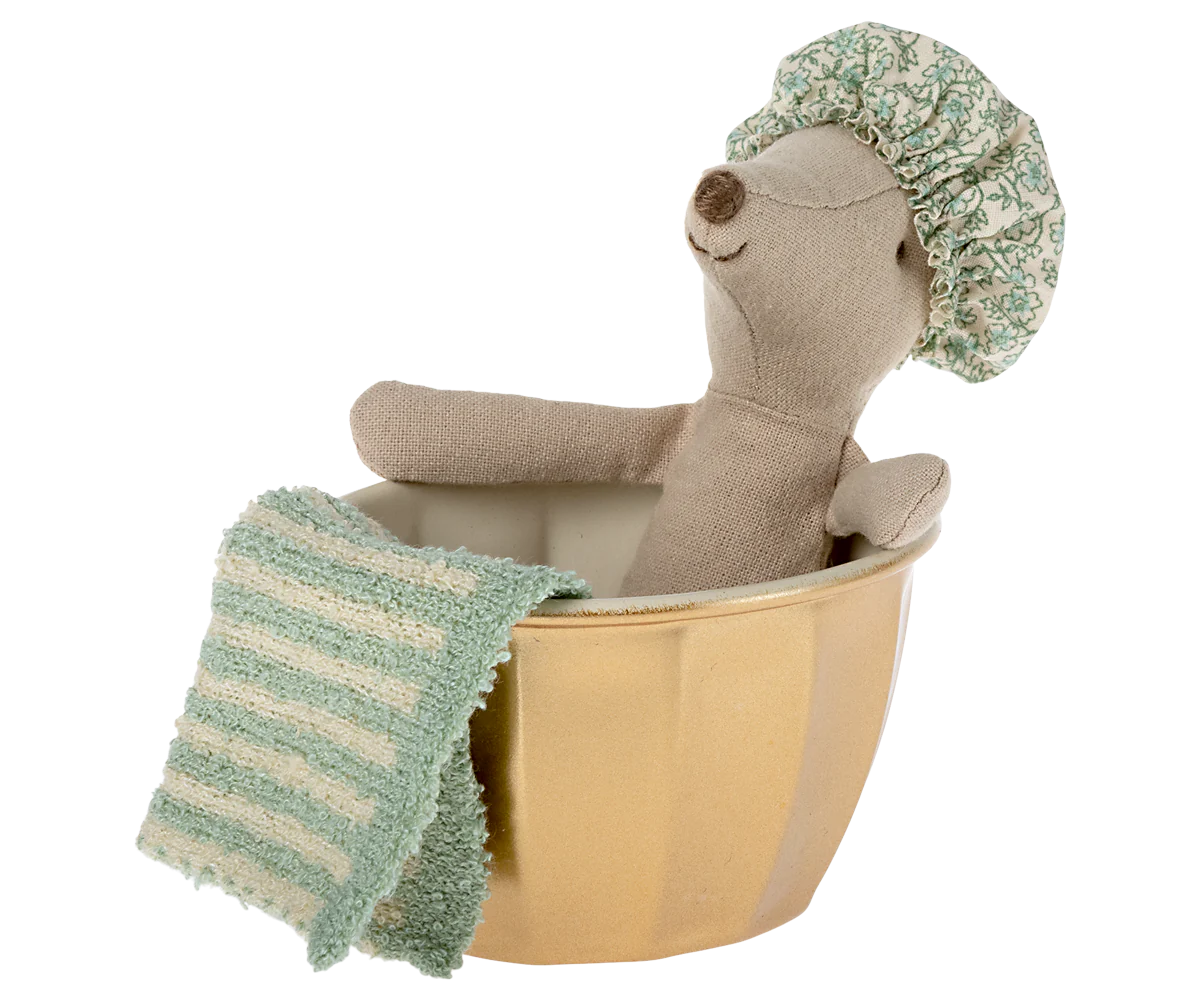 A Maileg Mouse by Maileg, wearing a patterned shower cap, sits in a gold-colored tub with a green and white striped towel on the side. Colors may vary for each mouse.