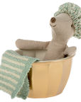 A Maileg Mouse by Maileg, wearing a patterned shower cap, sits in a gold-colored tub with a green and white striped towel on the side. Colors may vary for each mouse.