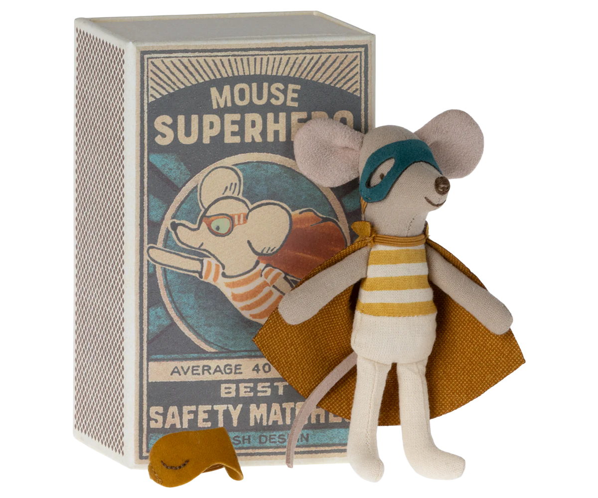 A Maileg Mouse toy from Maileg wears a striped outfit, superhero cape, and mask, standing in front of a "Mouse Superhero" matchbox with an illustration of the costumed mouse.