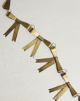 The Collectors Garland -Bow by Accent Decor features gold-colored bows linked by small rings, arranged diagonally on a light surface—making it a perfect unique holiday decoration.