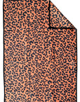 The Faire Double Sided Hand Towel features a rectangular waffle weave microfiber design with orange and black leopard print on both sides. One corner is folded to show the reversible pattern—an eco-friendly holiday choice.