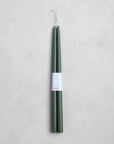 A pair of 18" Taper Candles by The Floral Society, featuring an elegant dark green design with white labels, set against a light gray textured background.