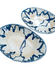The Demario Bowls by The Import Collection feature two oval ceramic pieces with cream bases and dark blue abstract patterns, adding a hand-painted, artistic accent to your handcrafted home decor.