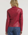 A person with long blonde hair is shown from the back, wearing the JAKETT Allison Burnished Leather jacket with blue jeans against a plain white background.