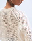 A close-up of a person wearing the White + Warren Cashmere Mesh Sweatshirt in white, highlighting the textured mesh knit on the back and shoulder. The model has short hair and a small hoop earring.
