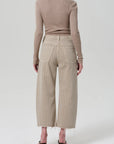 A person wears a fitted, long-sleeve beige top with Citizens Of Humanity/AGOLDE Ayla Raw Hem Crop high-waisted, wide-leg pinstriped pants in rigid cotton, relaxed rise, standing with their back to the camera against a plain light background.