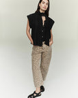 A woman with long dark hair and a neutral expression wears the Miro off white barrel leg wide-leg denim pants by Citizens Of Humanity/AGOLDE, paired with a sleeveless black top, scarf, and black sandals against a light background.