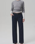 A person stands against a plain light background wearing Citizens Of Humanity Annina Pocket Trouser wide-leg jeans in dark indigo denim, paired with a fitted grey sweater with white sleeves and black sandals. Their face is not visible.