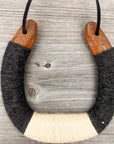 The Faire Lucky Horseshoe features rustic, rusty metal ends and is wrapped in black, gray, and white yarn. Hung on a black cord, it makes perfect upcycled home decor for a cozy touch.