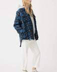 A person with long hair wears a blue and black Denimist CPO SHIRT JACKET over a gray hoodie, white cuffed cotton pants, and light-colored Converse sneakers, standing against a plain white background.