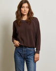 A woman with long brown hair wears the Perfectwhitetee Ziggy Reverse LS Sweatshirt in dark brown with bracelet-length sleeves and blue jeans, standing against a plain light background, looking at the camera neutrally.