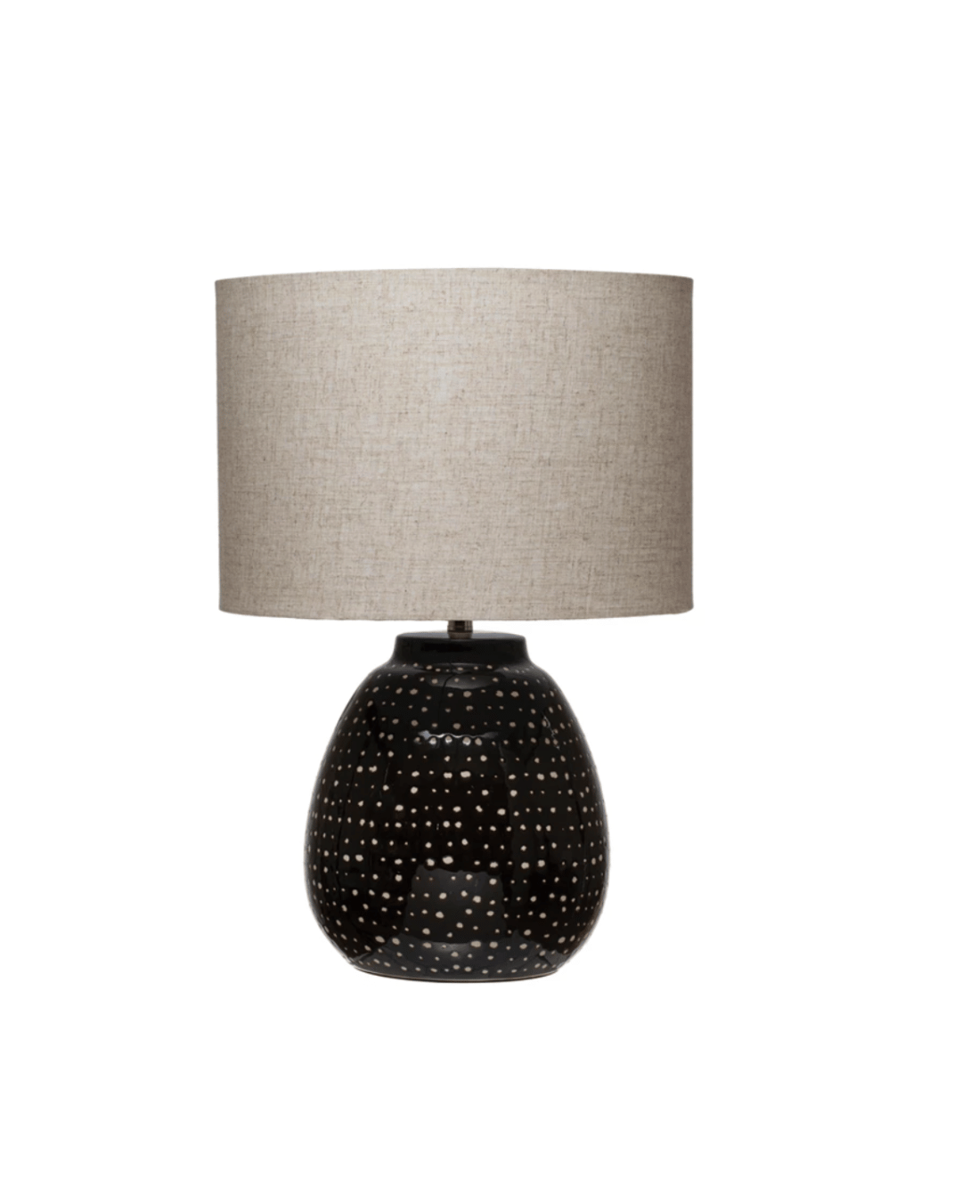 A Stone Table Lamp Black White Dots by Creative Co-op with a textured, beige drum shade and a glossy black ceramic base featuring small, round perforations allowing light to pass through, perfect for a Scottsdale Arizona bungalow.