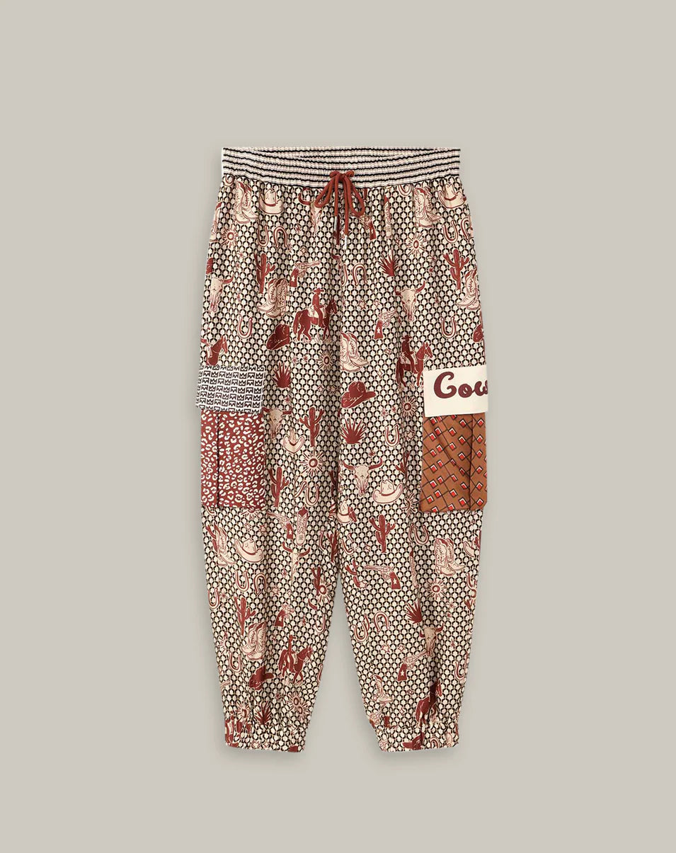 The Gianna Cargo Pants by Me369 feature a red, white, and brown rodeo print with geometric designs, an elastic striped waistband, drawstring, patch pockets, and gathered cuffs, shown on a plain background.