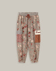 The Gianna Cargo Pants by Me369 feature a red, white, and brown rodeo print with geometric designs, an elastic striped waistband, drawstring, patch pockets, and gathered cuffs, shown on a plain background.
