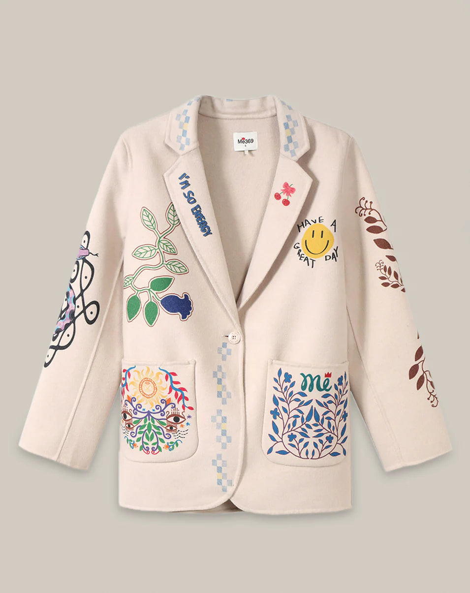 The Juliana Wool Jacket by Me369 is an off-white women's blazer with colorful plant, flower, smiley face, and abstract designs on the pockets and sleeves. It features a single button closure and notched collar for timeless style.
