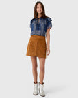 Hunter Bell NYC Dottie Skirt styled with blue patterned top and white cowboy boots, casual modern look.