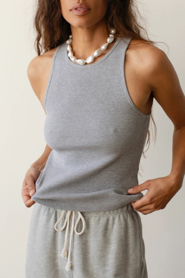 A woman in a gray Donni Rib Tank and matching drawstring pants, accessorized with a large pearl necklace, posing with one hand on her hip in Scottsdale, Arizona. Only her torso and lower face are visible.