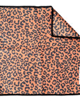 A square waffle weave microfiber washcloth from Faire features an orange and black leopard print, black edges, a folded corner showing the reverse, and an eco-friendly design. A white tag with the brand name "Faire" is attached.