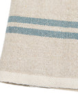 A close-up of Caravan’s Vintage Linen Towels Set-2 in beige, featuring two parallel blue stripes near the edge, highlights the rustic charm and texture of these classic table linens.