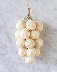 Faire’s Handcrafted Grapes Soap features round, pale white soaps shaped like a grape cluster and tied with twine, displayed on a light marble surface.