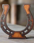 The Faire Horseshoe Rustic Western Doodad features a weathered, upright horseshoe design on wood, ideal as rustic decor for any western-themed space.